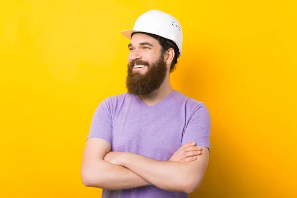 Confident bearded man is standing with crossed arms over yellow background.