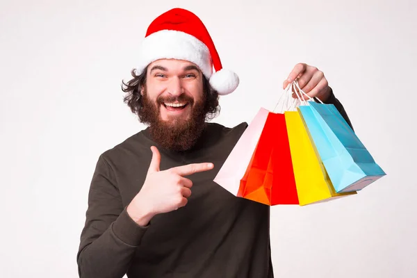 Ενθουσιασμένος γενειοφόρος άντρας δείχνει τις τσάντες που αγόρασε τα Χριστούγεννα.. — Φωτογραφία Αρχείου