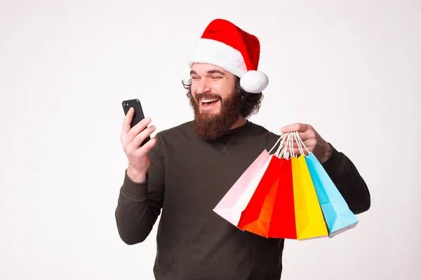 Make your purchases online through your phone. Bearded man is holding some shopping bags. — Stock Photo, Image