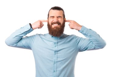 Sakallı adam parmaklarıyla kulaklarını kapatıyor..