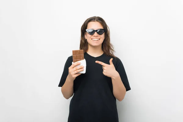 Улыбающаяся девушка указывает на плитку шоколада. — стоковое фото