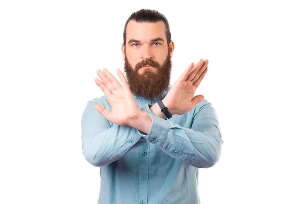 Hombre barbudo joven está haciendo la señal prohibida sobre fondo blanco. — Foto de Stock