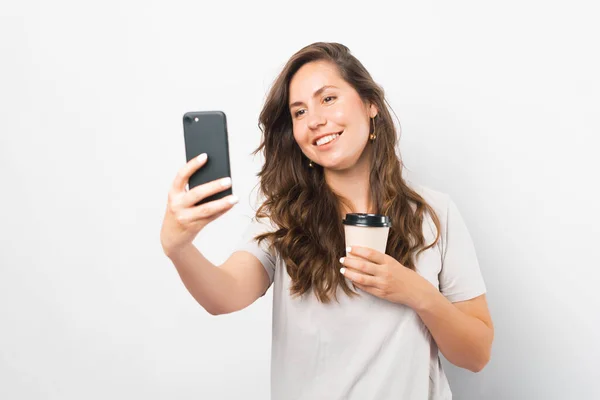 Joyful jovem mulher está tomando uma selfie enquanto segurando ela tirar xícara de café. — Fotografia de Stock