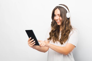 Beyazlar içindeki kız müzik dinlerken tabletini kullanmaktan zevk alıyor..