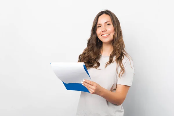 Retrato de uma mulher sorridente segurando uma área de transferência sobre fundo branco. — Fotografia de Stock