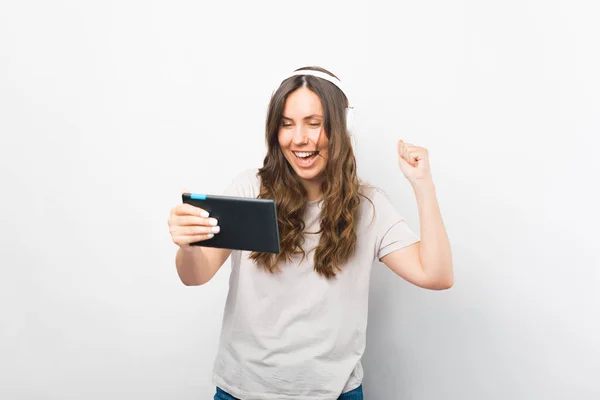Cheerful girl has won in betting or gaming on her tablet. — Stock Photo, Image