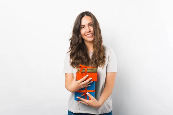 Agradable joven mujer está sosteniendo algunas cajas de regalo sobre fondo blanco. — Foto de Stock