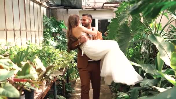 Filmación de feliz pareja recién casada, novio llevando novia en brazos — Vídeo de stock