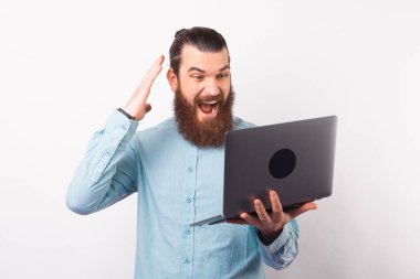 Sakallı adam dizüstü bilgisayara bakarken çok heyecanlı..
