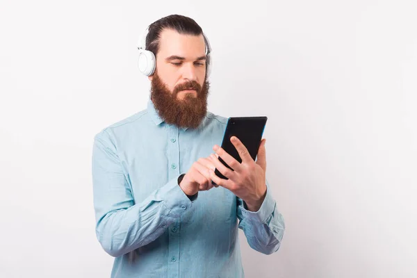 Jeune homme sérieux utilise une tablette et porte des écouteurs. — Photo