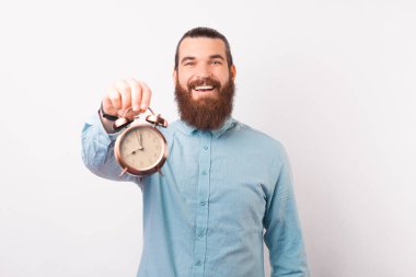 Genç sakallı adam kameraya çalar saati gösteriyor..