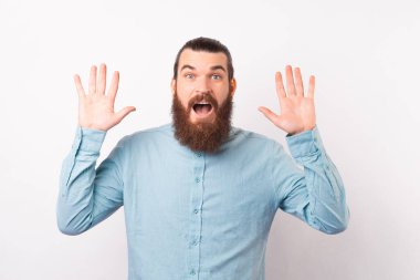 Şok olmuş sakallı adam kameraya bakarken el ele tutuşuyor, ağzı açık..