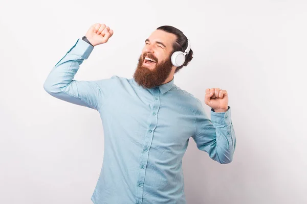 Bailando barbudo hombre está usando algunos auriculares sobre fondo blanco. — Foto de Stock