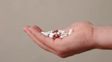 Çeşitli ilaç ve kapsüllerden oluşan, toplumdaki sağlık ve ilaçları sembolize eden bir el.