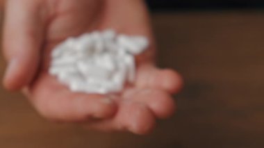 Bir kişinin elinde çeşitli beyaz tabletler sergilenmekte olup, bu tabletler önemli tıbbi temayı vurgulamaktadır.