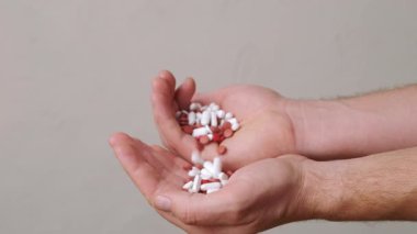 Renkli tablet ve kapsüllerden oluşan canlı bir çeşidi dikkatlice tutan ellerin yakın plan görüntüsü, sağlık için gereklidir.