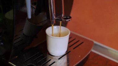 Kahve sanatı yakın plan, dumanı tüten espresso bardağa dökülüyor, ev kahvecisi zengin kremalı espresso yapıyor.