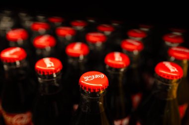 Chisinau, Moldova, 2 Aralık 2025. Kapalı cam soda şişeleri, kırmızı kapaklar, karamsar aydınlatma, sığ alan derinliği, parlak gölgeler, eski moda.