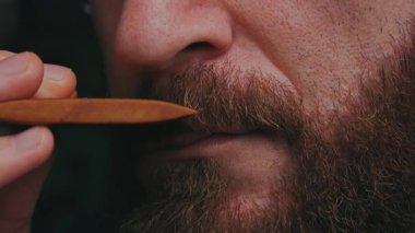 Yakından çekilen adam, bıyık ağdası sürerken, dudak hizasında ahşap şaplak, bıyık ipliklerini yumuşatırken kehribar kremi sürerken, dikkat et.