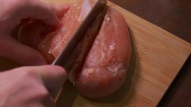 Çiğ tavuk göğsü ince dilimlenir, bıçağa yakın durulur, tahta tahta pano, sabit eller filetoları pişirmeye hazırlar, ısıtır.