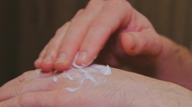 Kapalı el, beyaz kremi elinin arkasına sürerek, parmaklarını nazikçe cildine sürterek, görünür bir yüzükle, rahatlatıcı bir cilt kremi sürerek,