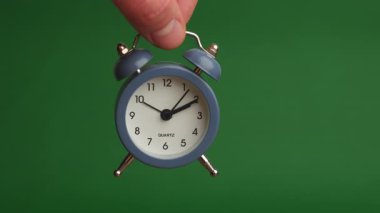 Elle tutulan Mavi Alarm Saati Yeşil Arkaplan 'a karşı Kapatma, Analog Eller