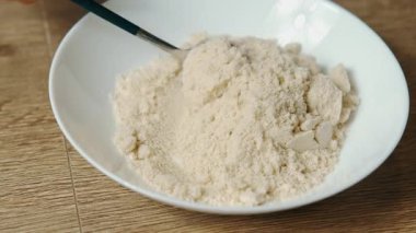 Tahta masadaki Macro yakın çekim pudrası, kaşık Scooping ve ince un benzeri dokular, yumuşak taneli