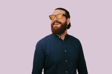 Stüdyoda gülümseyen sakallı adam, lavanta arka planda düşünceli bir portre, kehribar gözlükler ve deniz kuvvetleri.
