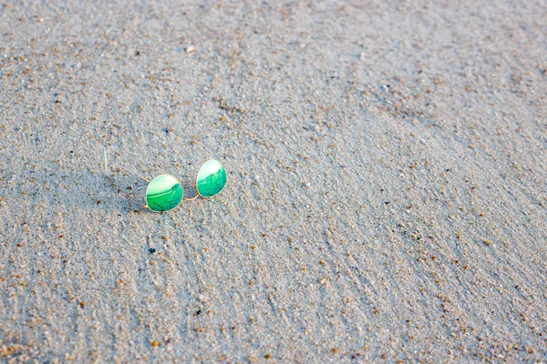 Gafas de sol verdes en la arena —  Fotos de Stock