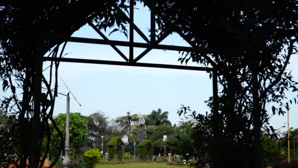 Foliage entrance into garden with clock. — Stock Video