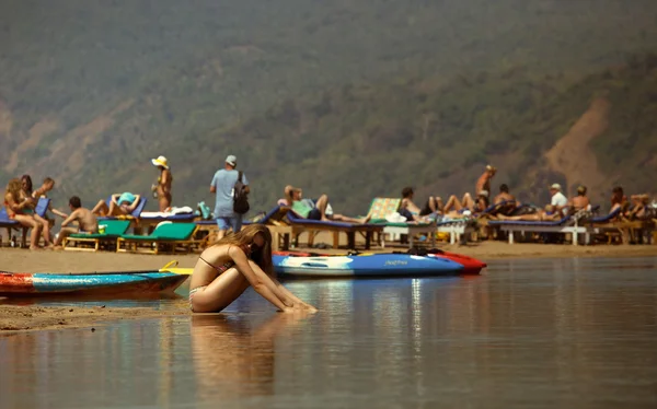 tekne yakınındaki yansıması ile plajda bikini ve güneş gözlüğü seatting genç kız