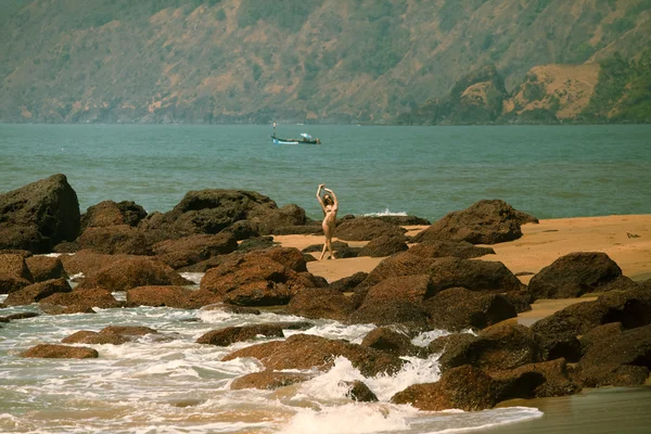 Bikini güzel vücut ve sahilde kırmızı taşlar yakınındaki güneş gözlüğü ile genç kız