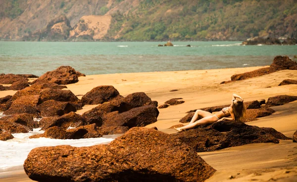 Bikini güzel vücut ve sahilde kırmızı taşlar yakınındaki güneş gözlüğü ile genç kız