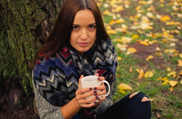 Menina bonita descansando e bebendo café sentado no jardim de outono — Fotografia de Stock