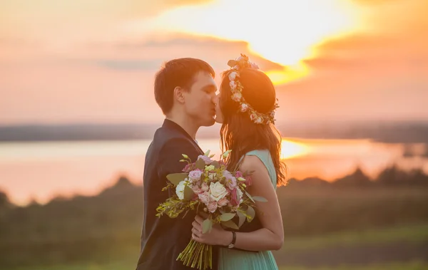 Молода закохана пара на свіжому повітрі - цілується на фоні заходу сонця біля води — стокове фото