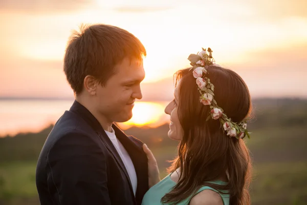 Молода пара закохалася на свіжому повітрі - дивлячись один на одного на фоні заходу сонця — стокове фото