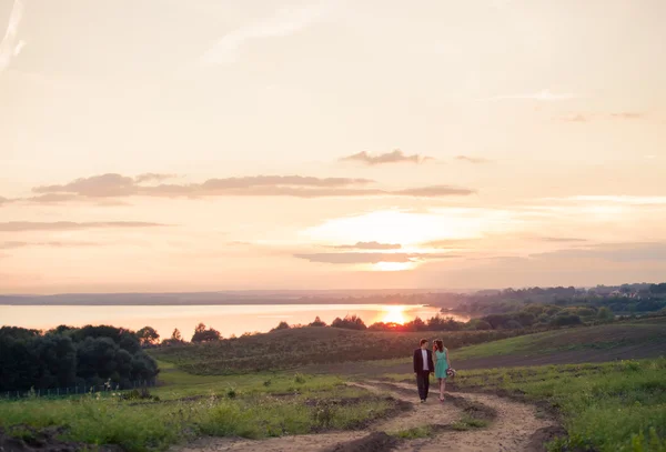 Genç bir çift aşık, zevk çayır suya yakın günbatımında günbatımı - açık