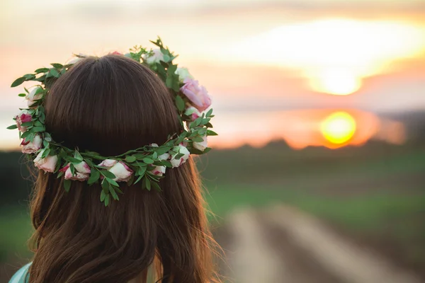 Kız zevk çayır günbatımında bir çelenk