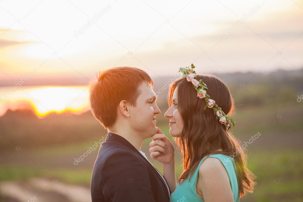 A Young couple in love outdoor at the sunset - looking at each other at the sunset background