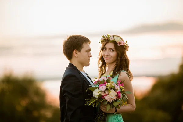 Gün batımında - açık aşık genç bir çift bir çelenk kız kameraya doğru görünüyor.