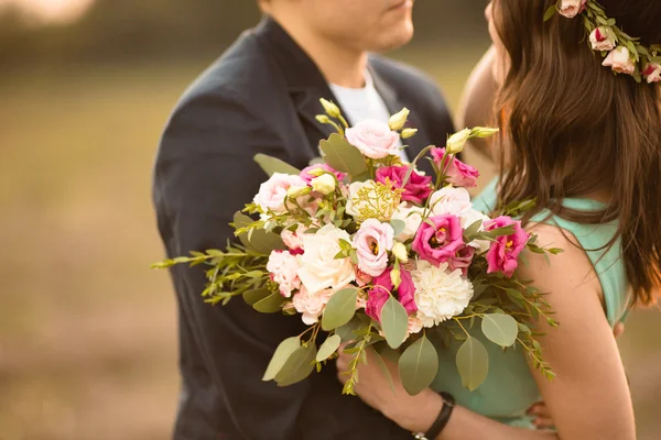Молода пара закохана на свіжому повітрі на заході сонця - чоловік дарує квіти — стокове фото