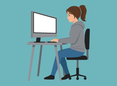 Gri kapüşonlu genç bir kadın masaüstü bilgisayarında çalışıyor.