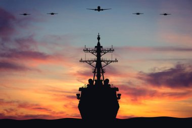 Bir savaş gemisinin silueti F-35 savaş jetleriyle tepemizde uçarken bir uçak gemisine günbatımının arka planına kadar eşlik eder. Amerikan Hava Kuvvetleri. Askeri tatbikatlar. Ülkenin savunması. Savaş.