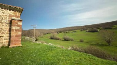Çimenli tepede kırmızı kiremitli ve ağaçlı geleneksel taş kilise.