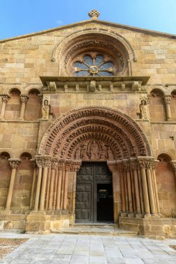 Tarihi bir kilisenin görkemli görünüşü. Karmaşık oymalar, bir gül penceresi ve berrak mavi gökyüzünün altında dekoratif kemerler..