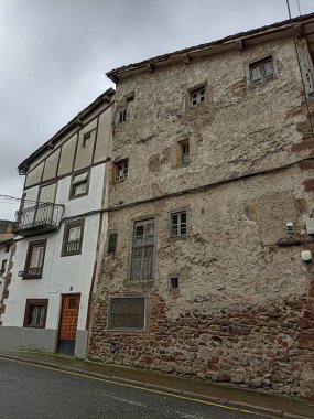 Çürümüş yüzüyle eski bir yapı ve dar sokaktaki ahşap panjurlar.