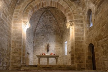 Taş duvarları, kubbeli tavanı ve basit sunak süslemesi olan tarihi Roma kilisesi..