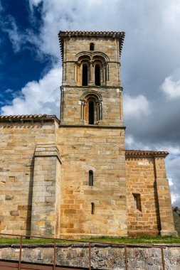 Bulutlu gökyüzünün altında belirgin çan kulesi ve taş cepheli tarihi bir keşiş..