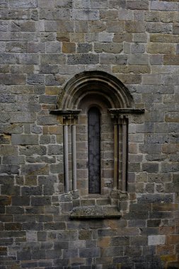 Tarihi bir cephede küçük sütunlar ve taş kemerlerle çerçevelenmiş Romanca pencereyi daralt.