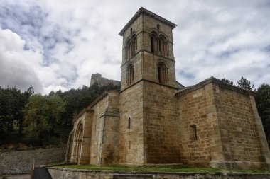 Bulutlu gökyüzünün altında belirgin çan kulesi ve taş cepheli tarihi bir keşiş..